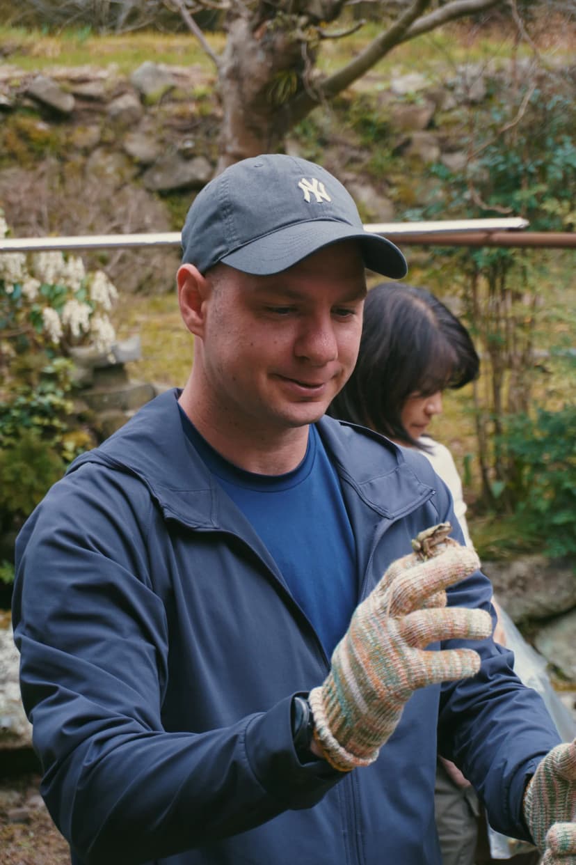 Jason wearing gloves and examining a plant while foraging in Japan