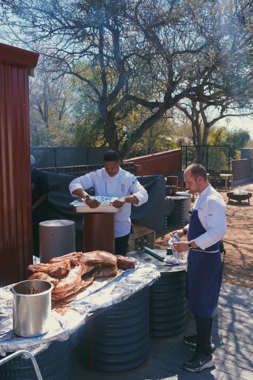 Jason cooking outside with a chef beside the smoking grill at Kruger Shalati