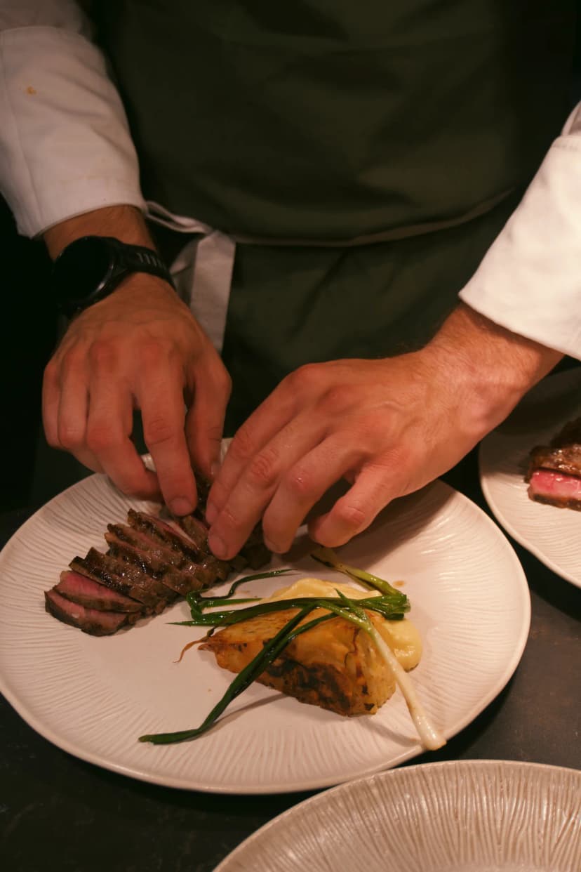 Hands arranging slices of meat on a plate during service in Sumba